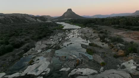 Aerial-view-moves-away-shot,-Scenic-view-of-rock-formation-and-river-La-Purisima-Baja-California-sur,-Mexico,-El-Pilón-mountains-in-the-background