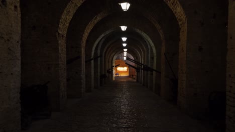 Langer-Korridor-Mit-Gewölbten-Steinwänden-In-Der-Mittelalterlichen-Festung-Von-Gjirkastra,-Gefüllt-Mit-Kanonen-Und-Waffen