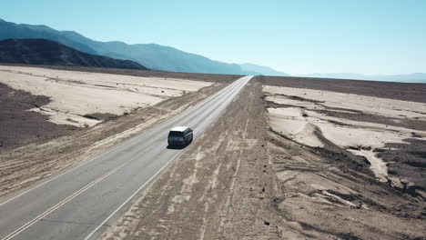 Tracking-Aerial-Shot-Of-Car-Travelling-Through-Desert-Landscape-In-Death-Valley-National-Park,-California