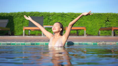 Girl-in-pool-raises-her-arms-smiling-satisfied