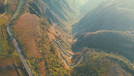 Top-down-cinematic-view-of-mountain-tropical-rainforest-road,-Serra-Do-Rio-Do-Rastro-and-the-mountains-of-Santa-Catarina-at-sunrise