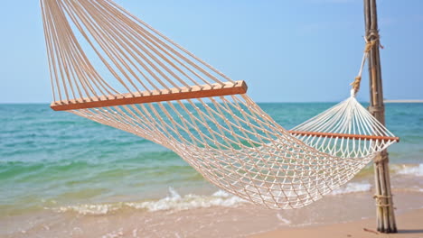 Empty-hammock,-Rope-hammock-swinging-in-the-gentle-summer-breeze-blowing-along-the-sandy-coast