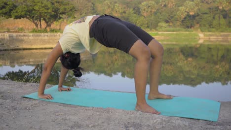 Indian-girl-doing-upward-bow-weel-pose-urdhva-dhanurasana-yoga-pose-by-the-lakeside