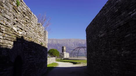 Stone-walls-of-citadel-in-Gjirkaster-with-clock-tower-on-mountains-background