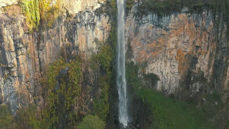 Tropical-rainforest-waterfall-big-rock-wall-located-in-Urubici-aerial-view,-Santa-Catarina,-Brazil