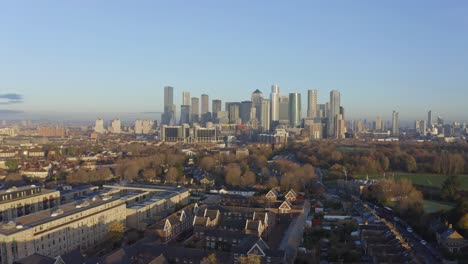 Rising-drone-shot-from-residential-buildings-to-canary-wharf-skyscrapers-at-sunrise