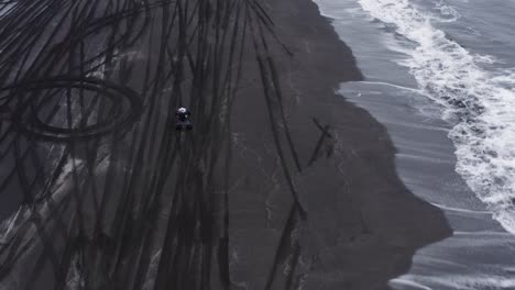 Man-on-quad-bike-accelerating-and-pulling-wheelie-on-black-beach-in-Iceland