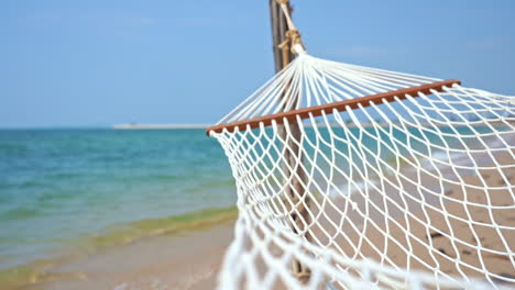 Empty-hammock-on-beach-and-turquoise-sea-in-background