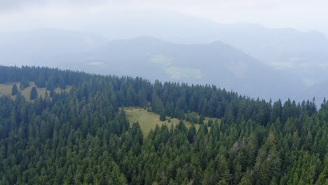 Dense-green-forest-with-layers-of-mountains-in-background