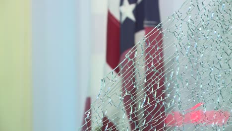 BROKEN-GLASS-IN-FOREGROUND-WITH-AMERICAN-FLAG-IN-BACKGROUND-DURING-RIOT