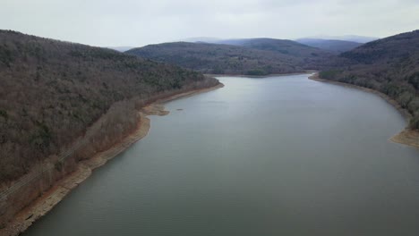 A-drone-flying-high-and-panning-sideways-over-a-pristine-mountain-lake-during-early-winter-in-northern-appalachia