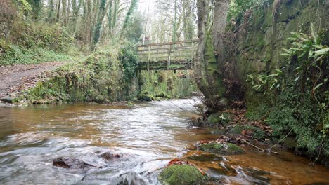 Old-rural-copper-mine-river-flowing-under-woodland-forest-wilderness-bridge-crossing