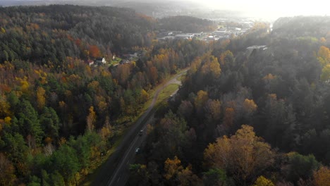 Aerial-flying-backwards-shot-of-road-in-a-valley-during-autumn-season