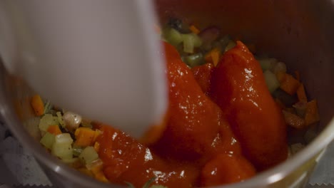 Adding-tomatoes-into-vegetable-mix-inside-cooking-pot