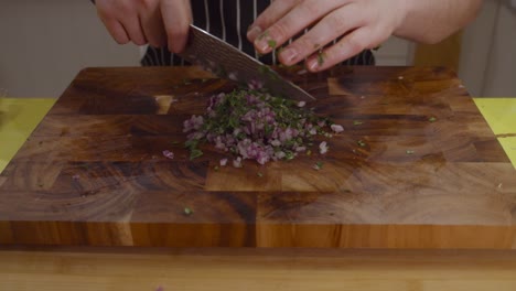 Chef-chops-onion-and-herbs-on-a-cutting-board