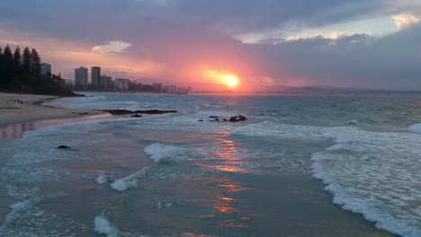 Drone-shot-going-sideways-over-ocean-waves-with-redish-beach-sunset-in-Australia-Coolangatta