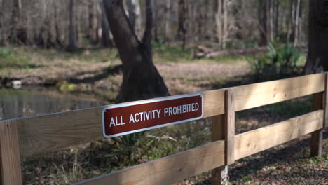 Schild-An-Einem-Eingezäunten-Schild,-Das-Besucher-Warnt,-Dass-Alle-Aktivitäten-In-Dem-Empfindlichen-Ökosystem-Des-Parks-Verboten-Sind
