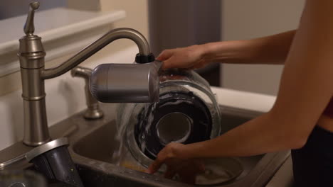 Woman's-delicate-hands-seen-washing-dishes---parts-of-a-juicer---in-the-kitchen-sink-in-slow-motion