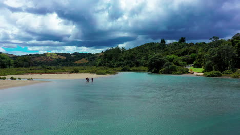 Gente-Cruzando-Un-Río-Azul-Poco-Profundo-En-Un-Día-Nublado-En-Nueva-Zelanda