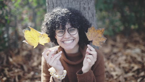 Silly-shy-girl-with-afro-curls-playing-with-autumn-dry-leaves