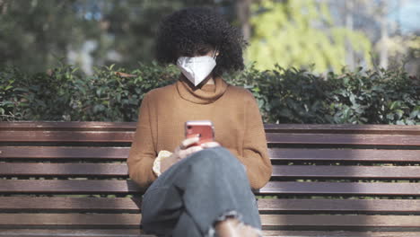 Niña-Negra-Introvertida-Enviando-Mensajes-De-Texto-En-Medio-De-Una-Pandemia-En-Un-Parque