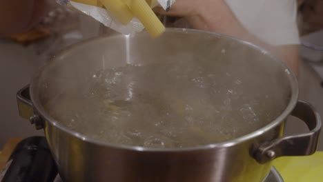 Putting-pasta-from-package-into-the-cooking-pot-with-hot-boiling-water