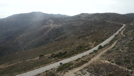 Atv,-Quad-Con-Pareja-Conduciendo-Por-Las-Carreteras-De-Montaña-De-Ios,-Grecia-Con-Toma-Aérea-De-Drones