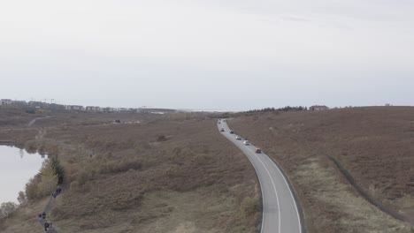 Elliðavatnsvegur-road-leading-into-Garðabær-town-on-cloudy-day,-aerial