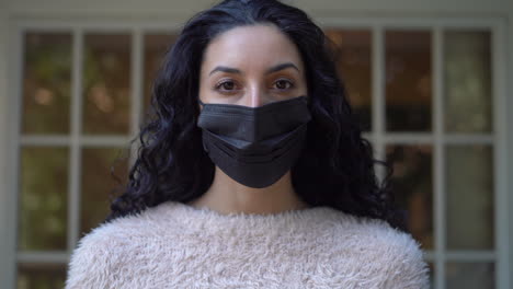 Young-attractive-Latina-woman-makes-sure-her-face-mask-fits-properly-then-removes-it-while-looking-at-the-camera