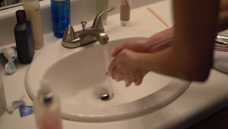 Frau,-Die-Ihre-Hände-Im-Waschbecken-Mit-Kosmetik-Und-Anderen-Hygieneprodukten-Rundum-Wäscht---Zeitlupe-Isoliert