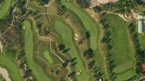 Aerial-overhead-view-of-a-golf-course-with-beautiful-abstract-patterns,-sand-traps,-trees-and-lakes