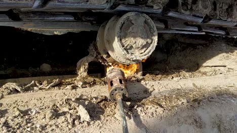 A-propane-tiger-torch-being-used-to-thaw-frozen-dirt-in-the-under-carriage-of-a-piece-of-construction-equipment