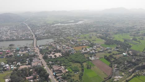 Aerial-view-of-Gingee-City,-Sangarabarani-River-and-hill-landscape-in-background-during-foggy-and-cloudy-day-in-India
