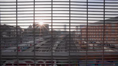 Train-passes-by-at-sunset-while-looking-through-a-steel-industrial-grid-at-the-North-South-connection-in-Marolles,-Brussels