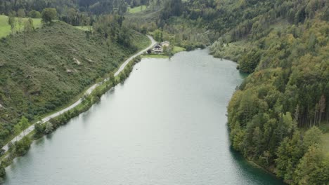 South-shore-of-Freibach-reservoir-dam-in-Austria-with-the-Stauseewirt-Greek-restaurant-far-away,-Aerial-dolly-out-reveal-shot