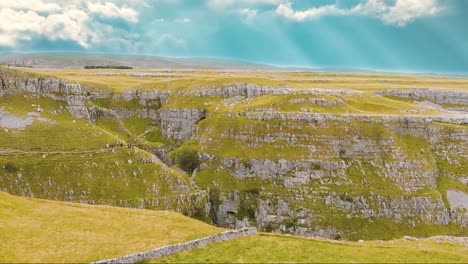 Drone-reverse-over-beautiful-Malham-Cove-landscape-with-suns-rays