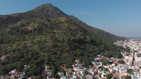 Aerial-shot-of-residential-houses-in-front-of-giant-overgrown-mountain-during-beautiful-weather-in-Tiruvannamalai,India