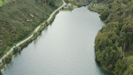 Freibach-reservoir-dam-with-the-Stauseewirt-Greek-specialty-restaurant-at-the-far-edge,-Aerial-tilt-up-reveal-shot