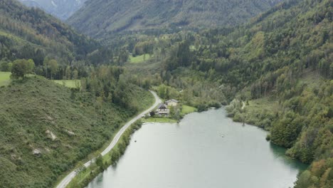 South-shore-of-Freibach-reservoir-dam-in-Austria-with-the-Stauseewirt-Greek-restaurant,-Aerial-dolly-out-reveal-shot