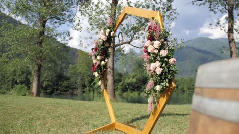 hexagonal-wedding-arch-with-flower-decoration-on-field-by-lake-before-ceremony