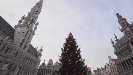 Low-wide-shot-of-Christmas-tree,-town-hall-and-guild-houses-on-the-Grote-Markt-in-Brussels,-Belgium