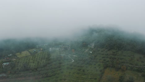 Drone-aerial-view-through-the-clouds-revealing-a-green-misty-forest-in-Guatemala