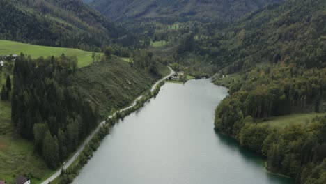 Freibach-reservoir-dam-in-Austria-with-some-farm-houses-near-the-south-shore,-Aerial-dolly-out-reveal-shot