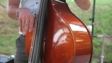 Closeup-of-man-playing-double-bass-with-fingers-outdoors,-slow-motion