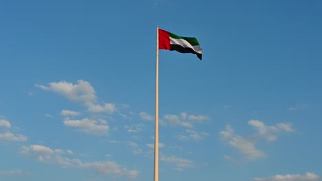 Bandera-De-Los-Emiratos-árabes-Unidos-Ondeando-En-El-Aire-Cielo-Azul-Nublado-En-El-Fondo,-Isla-De-La-Bandera-De-Sharjah,-Día-Nacional-De-Los-Emiratos-árabes-Unidos,-Imágenes-De-Invierno,-Video-De-4k