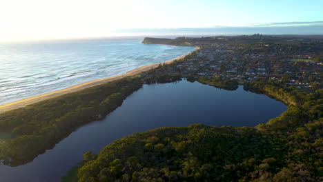 Wide-rotating-drone-shot-of-small-pond,-maritime-forest-and-coastline-at-Lennox-Head
