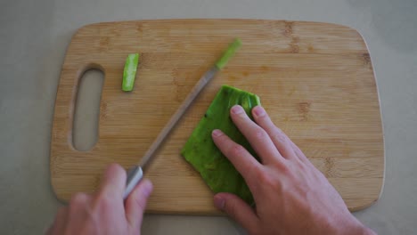 Looking-Down-Cutting-Nopales-with-Sharp-Knife-on-Cutting-Board