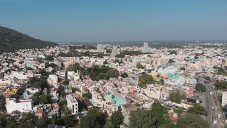 Aerial-flyover-bright-city-of-Tiruvannamalai-with-temple-towers-in-background-during-blue-sky-and-sunny-day