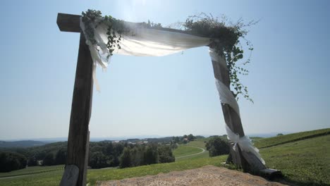 rustic-boho-wooden-wedding-arch-with-floral-decor-and-white-cloth,-dolly-shot