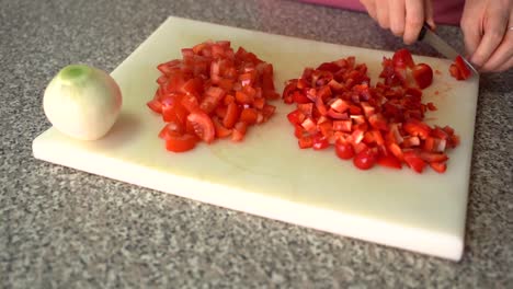 Frau-Schneidet-Rote-Paprika-Auf-Schneidebrett-Mit-Geschnittenen-Tomaten-Und-Weißen-Zwiebeln-Auf-Der-Seite
